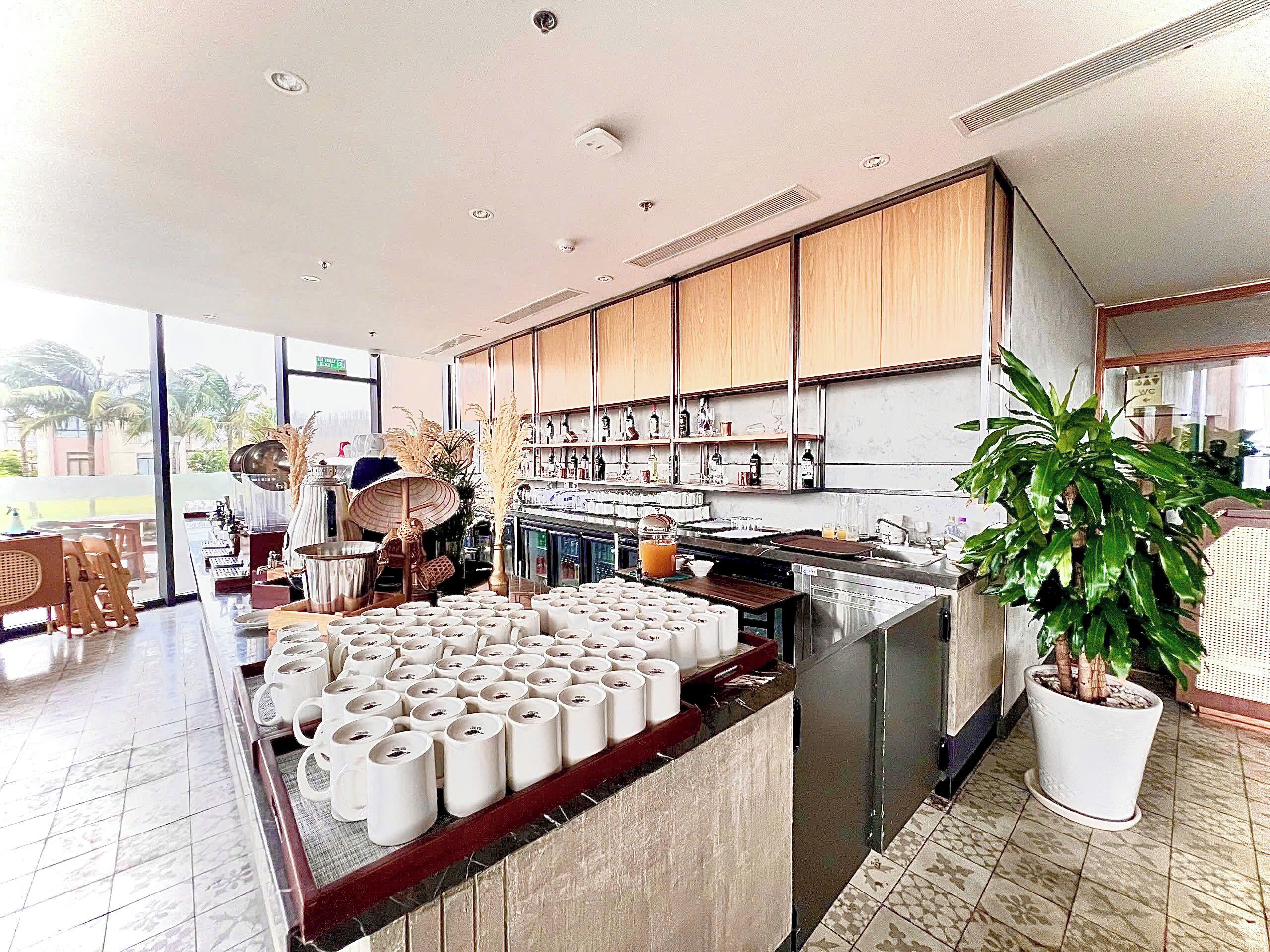 A modern kitchen with a central island, wooden cabinets, and a large potted plant.