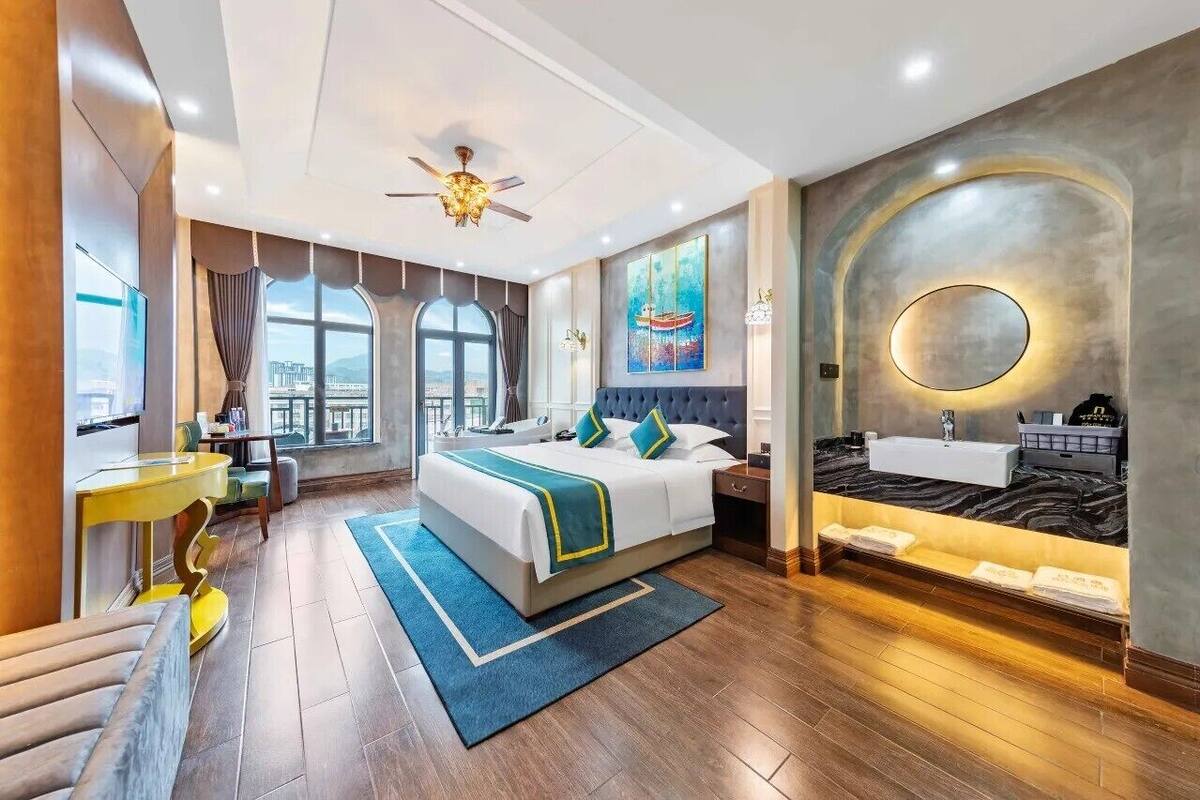 Una habitación de hotel moderna con una cama grande, un escritorio, un balcón y un baño con tocador.