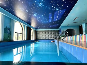 A swimming pool with a starry ceiling and a stone wall. - Xiao'en Castle Hotel Tianmenshan (Zhangjiajie)