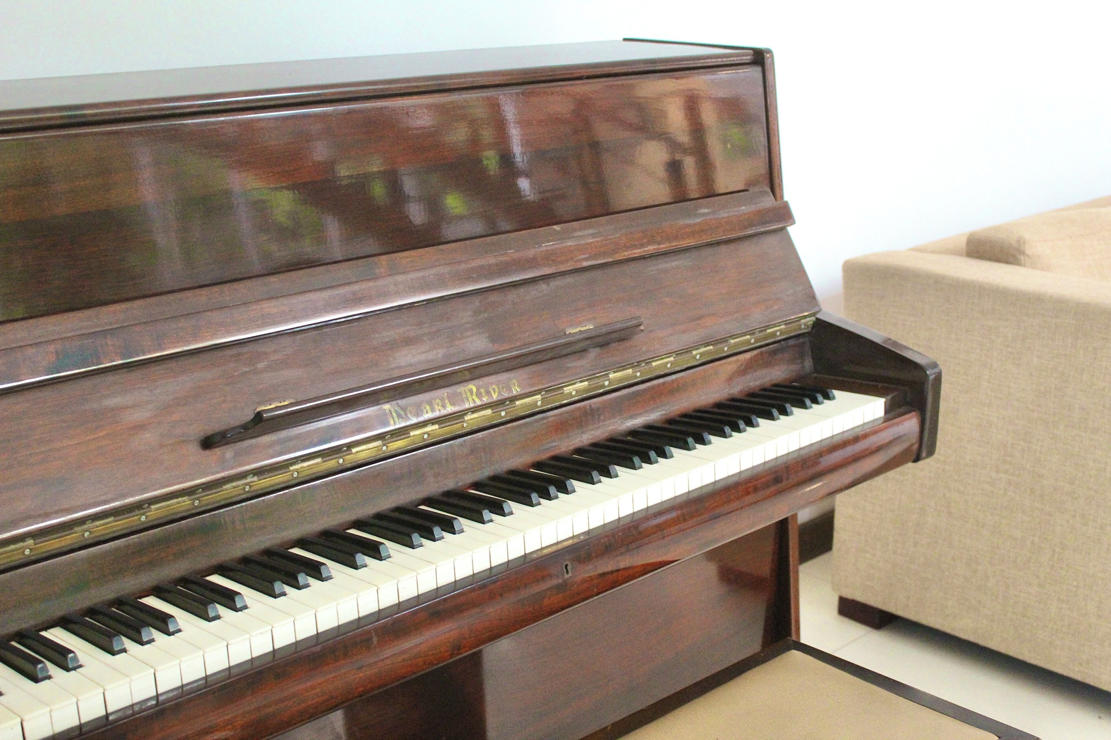 Un piano de cola de acabado oscuro con el nombre de la marca a la vista.