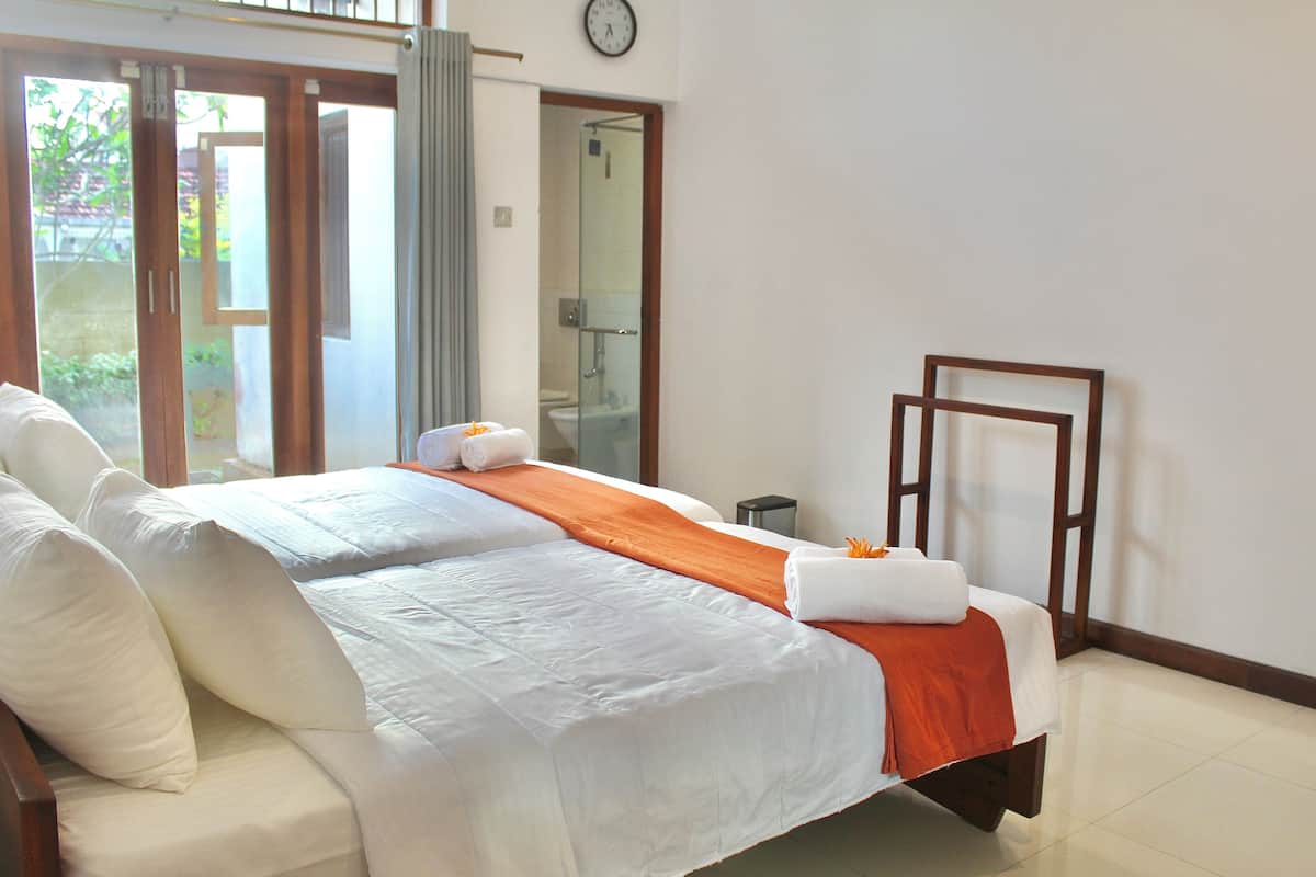 Habitación de hotel con una cama grande, una mesita y una zona de ducha visible a través de una puerta de cristal.