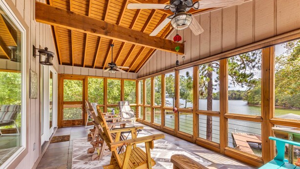 A covered outdoor area with wooden benches, a table, and a ceiling fan. - The Lady Bug on Lake Martin (Our Town)