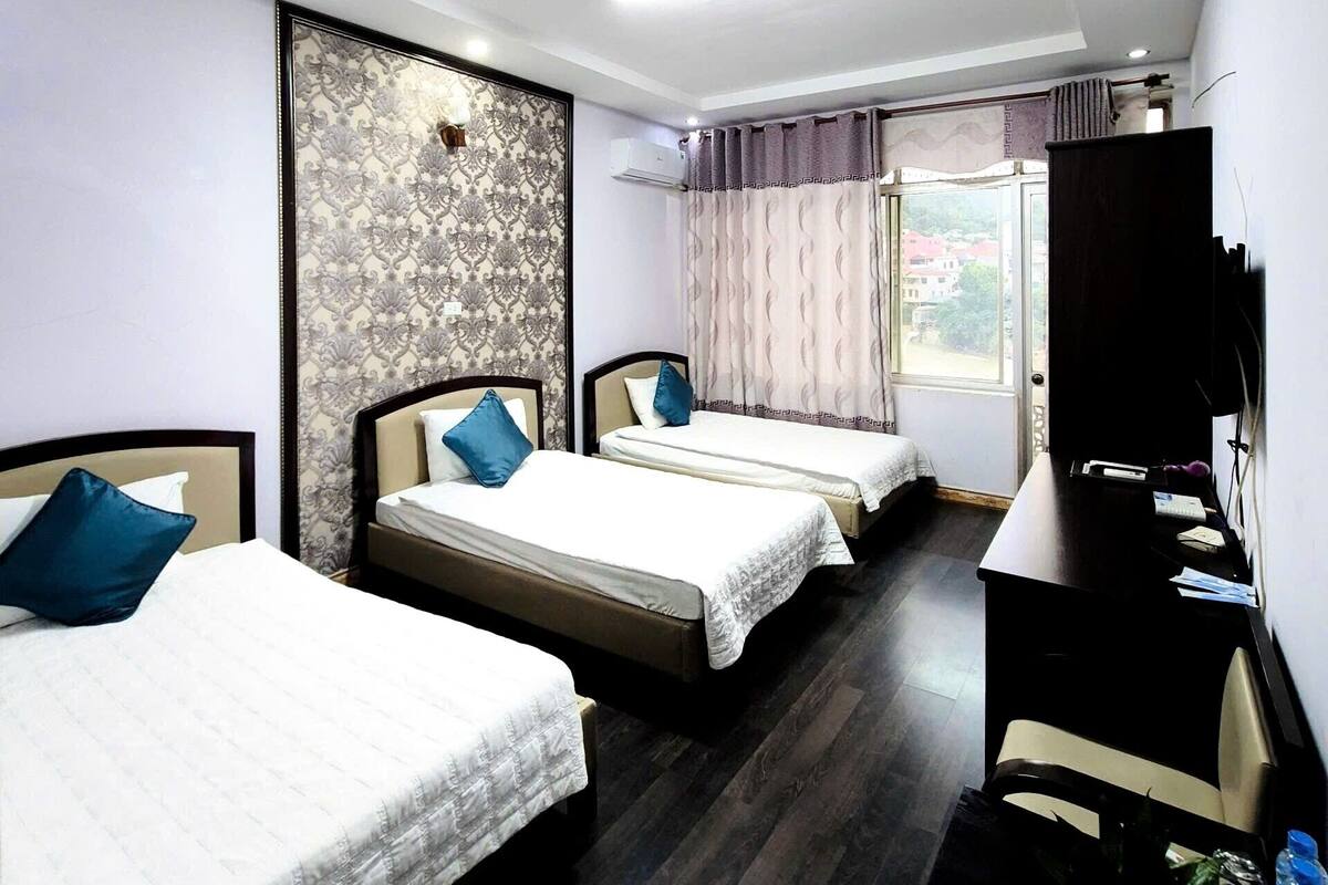 Una habitación de hotel con tres camas, un escritorio y una televisión.