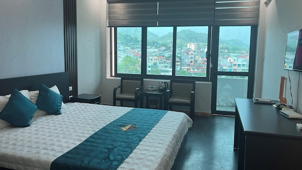 A hotel room with a large bed, two chairs, a desk, and a TV. - Bang Giang EcoGreen Hotel (Thuc Phan)
