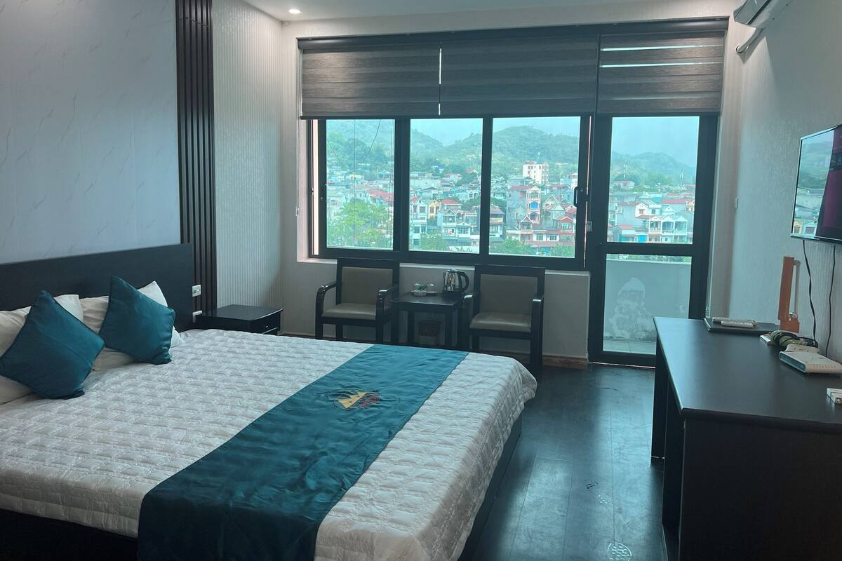 Una habitación de hotel con una cama grande, dos sillas, un escritorio y un televisor.