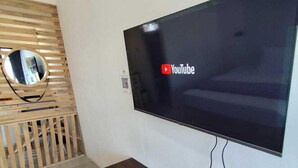 Moderni olohuone, jossa on suuri, seinälle asennettu litteänäyttöinen televisio, puinen säleikköseinäke ja sisäänrakennettu puinen konsolipöytä, jossa on laatikoita.