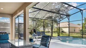Espaço coberto ao ar livre com piscina, assentos e vista do bairro.