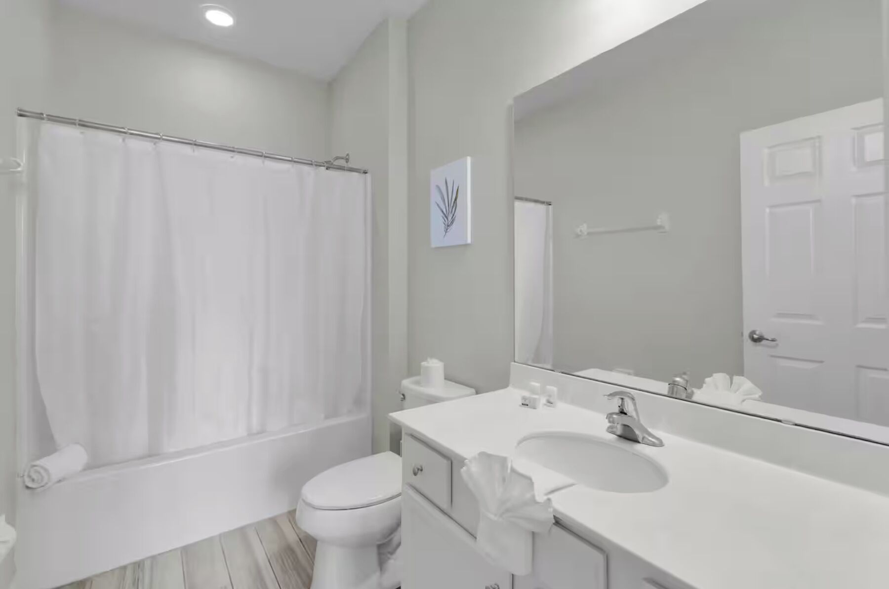Een moderne badkamer met douche, toilet, wastafel en een grote spiegel.
