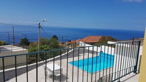 A rooftop pool with a clear view of the ocean, surrounded by residential buildings.