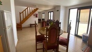 A dining area with a wooden table and chairs, a staircase, and a sliding glass door leading outside.
