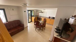 A compact living space with a dining area, kitchenette, and a sofa.