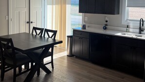 Una cocina moderna con comedor, suelo de madera y ventana que deja entrar luz natural.