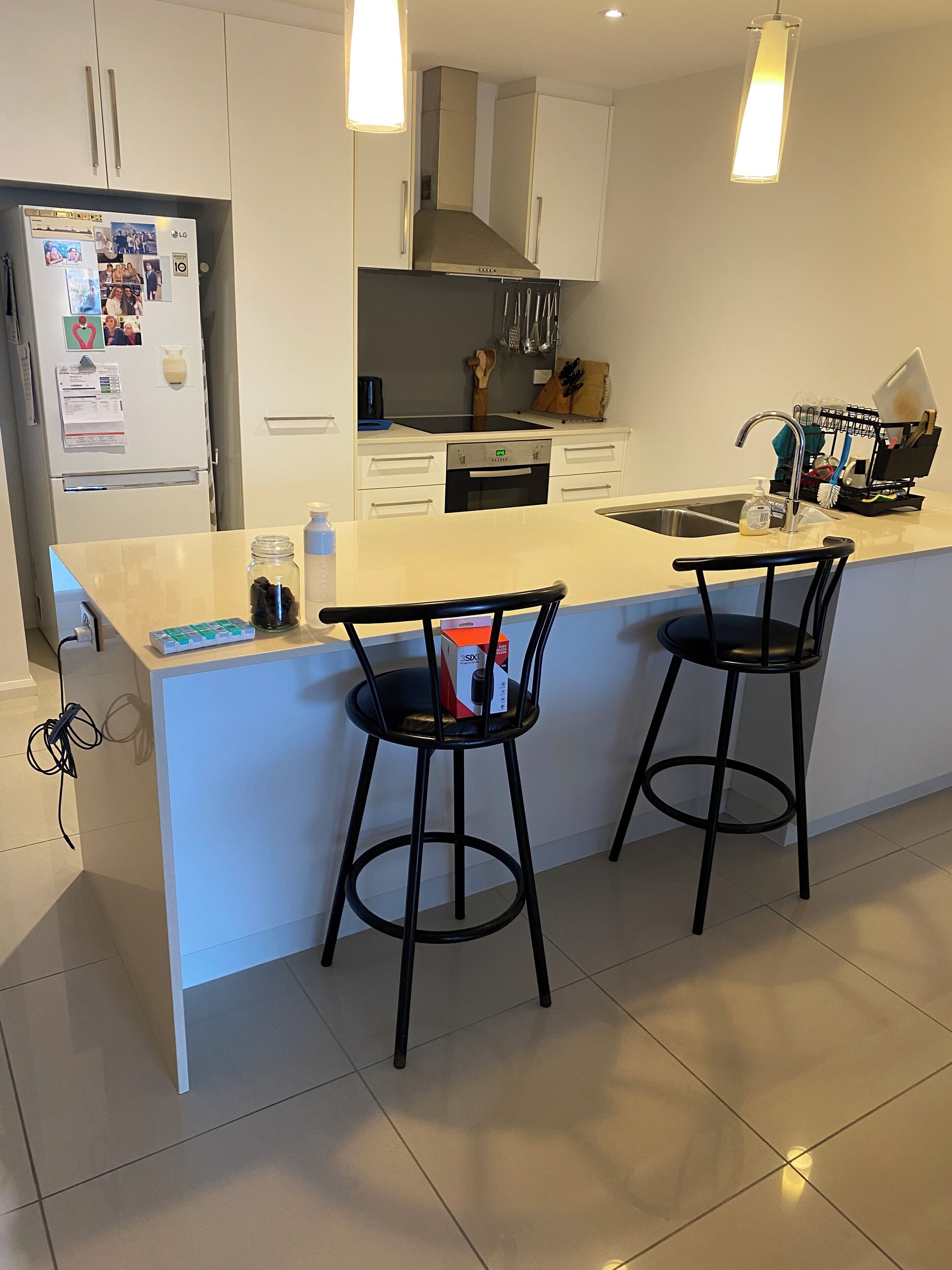 Una cocina moderna con armarios blancos, horno empotrado y una isla grande con dos taburetes de bar.
