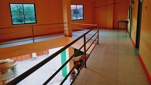 An interior with orange walls, a balcony with a metal railing, and a window with a view of the outside. - WJV INN TIMPOLOK (Lapu-Lapu)