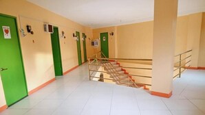 A hallway with green doors, a staircase, and tiled flooring. - WJV INN TIMPOLOK (Lapu-Lapu)