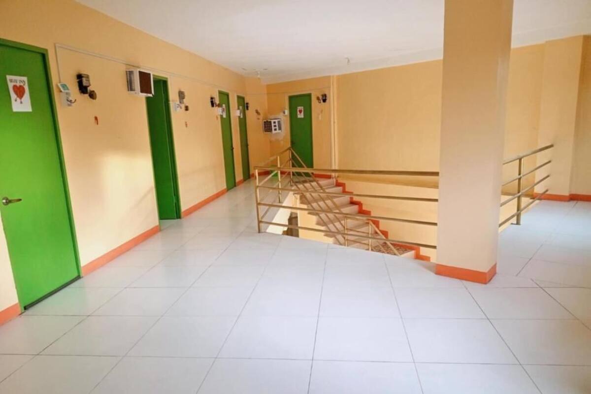 Un couloir avec des portes vertes, un escalier et un revêtement de sol carrelé.