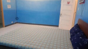 A bedroom with a bed, a door with a heart decoration, and a wall-mounted air conditioner. - WJV INN TIMPOLOK (Lapu-Lapu)
