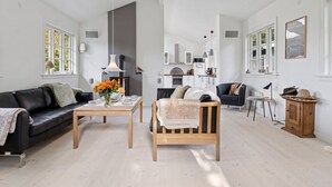 A spacious living room with a fireplace, a dining area, and a kitchen in the background. - "Domi" - 1.3km from the sea by Interhome (Græsted)