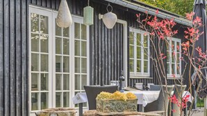 A rustic wooden building with large windows, outdoor seating, and decorative tree stumps. - "Domi" - 1.3km from the sea by Interhome (Græsted)