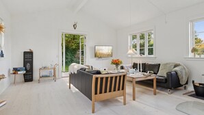 A spacious living room with a sofa, a coffee table, and a TV. There is a door leading to a garden. - "Domi" - 1.3km from the sea by Interhome (Græsted)