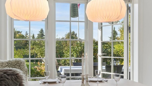 A dining area with a table set for four, large windows, and a view of greenery outside. - "Domi" - 1.3km from the sea by Interhome (Græsted)