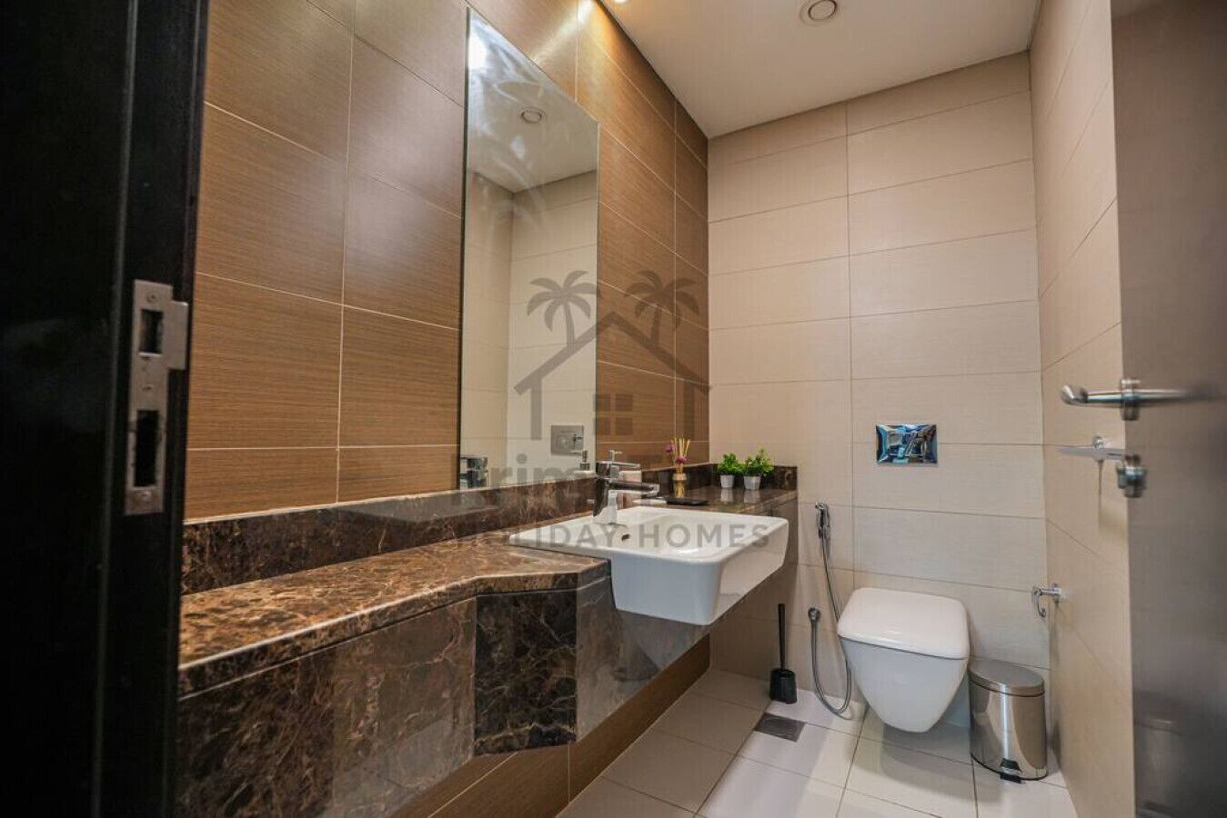 A modern bathroom with a marble countertop, a white sink, and a toilet.