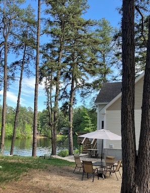 A lakeside property with a dining area, outdoor seating, and a view of the lake.