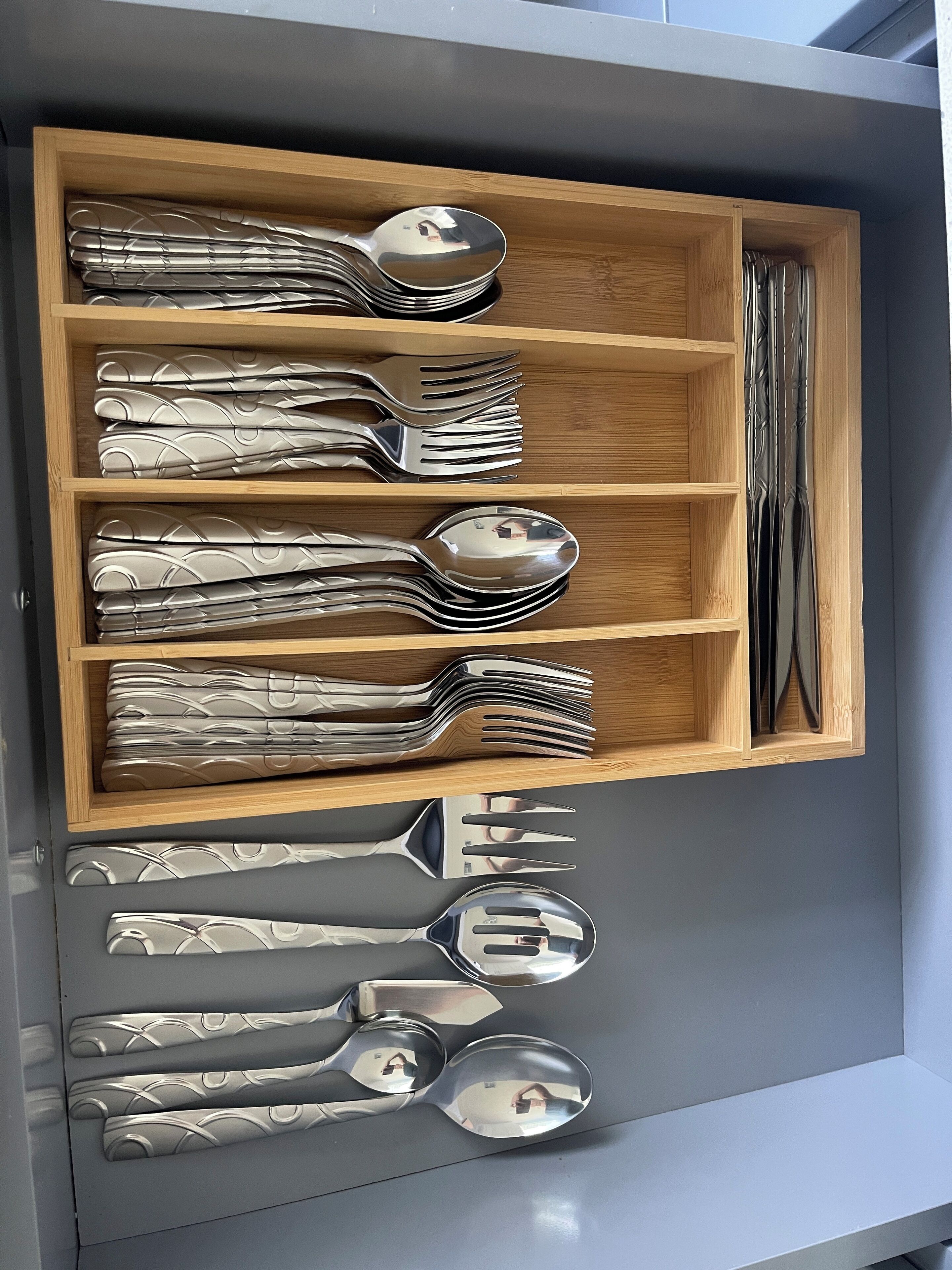 Un cajón con cubiertos ordenados, incluyendo tenedores, cucharas y un cuchillo.