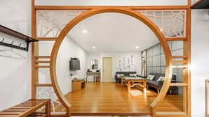 A modern living room with a wooden archway, a sofa, a coffee table, and a TV. - Kenting Hemingway (Hengchun)