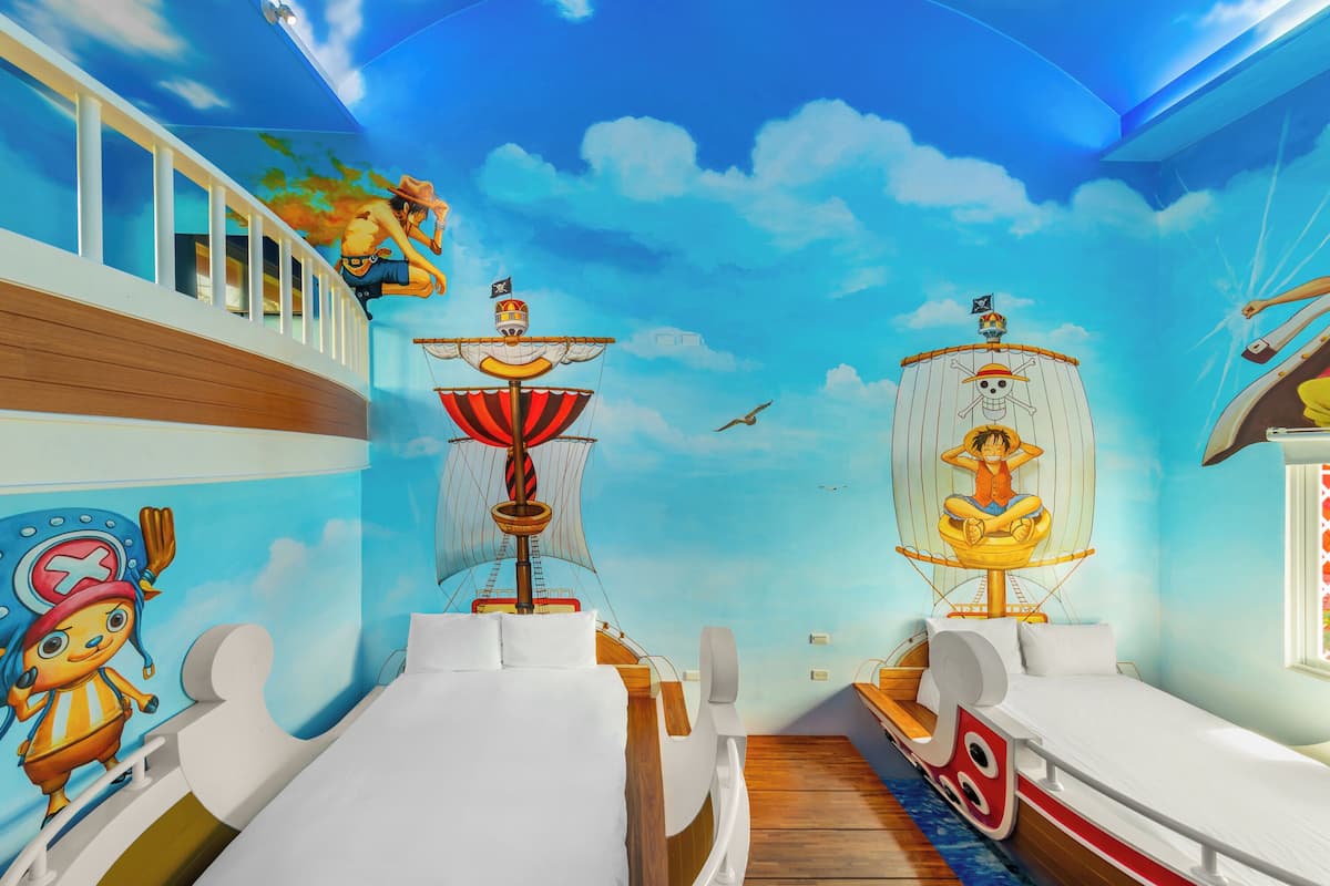 A children's room with two beds, a mural of a pirate ship, and a character on the left wall.