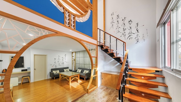 A modern interior with a wooden staircase, a dining area, and a living room with a sofa and a coffee table. - Kenting Hemingway (Hengchun)