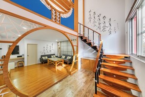 A modern interior with a wooden staircase, a dining area, and a living room with a sofa and a coffee table. - Kenting Hemingway (Hengchun)