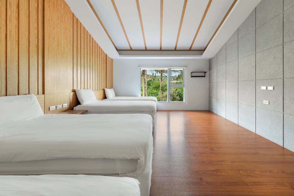 A modern hotel room with a wooden ceiling, large windows, and a view of greenery.