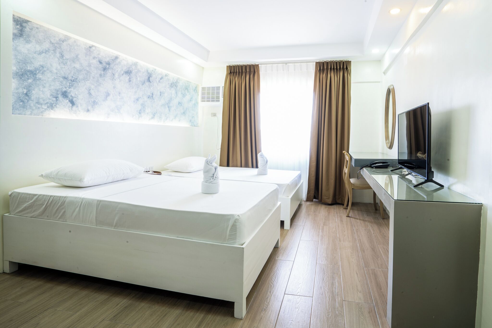 Een hotelkamer met een groot bed, een bureau, een televisie en een raam met gordijnen.