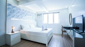 A modern bedroom with a bed, bedside table, and a desk with a chair.