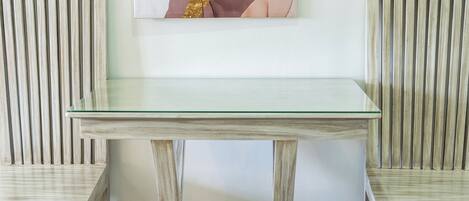 Una mesa con dos sillas, tablero de vidrio y estructura de madera.