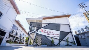 The Garden Galleries Boutique Hotel entrance with a modern design, potted plants, and string lights.