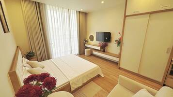 Quarto de hotel moderno com cama grande, televisão, sofá e guarda-roupa.