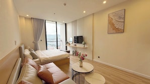 A modern hotel room with a large bed, a sofa, a small round table, and a TV.