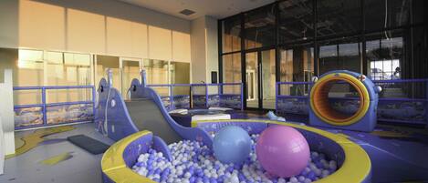 Un área de juegos interior con piscina de pelotas, toboganes y estructuras para escalar.