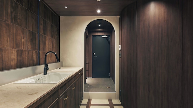 A modern bathroom with a sink, mirror, and dark wooden walls. - illi Noa Hamamatsucho (Tokyo)