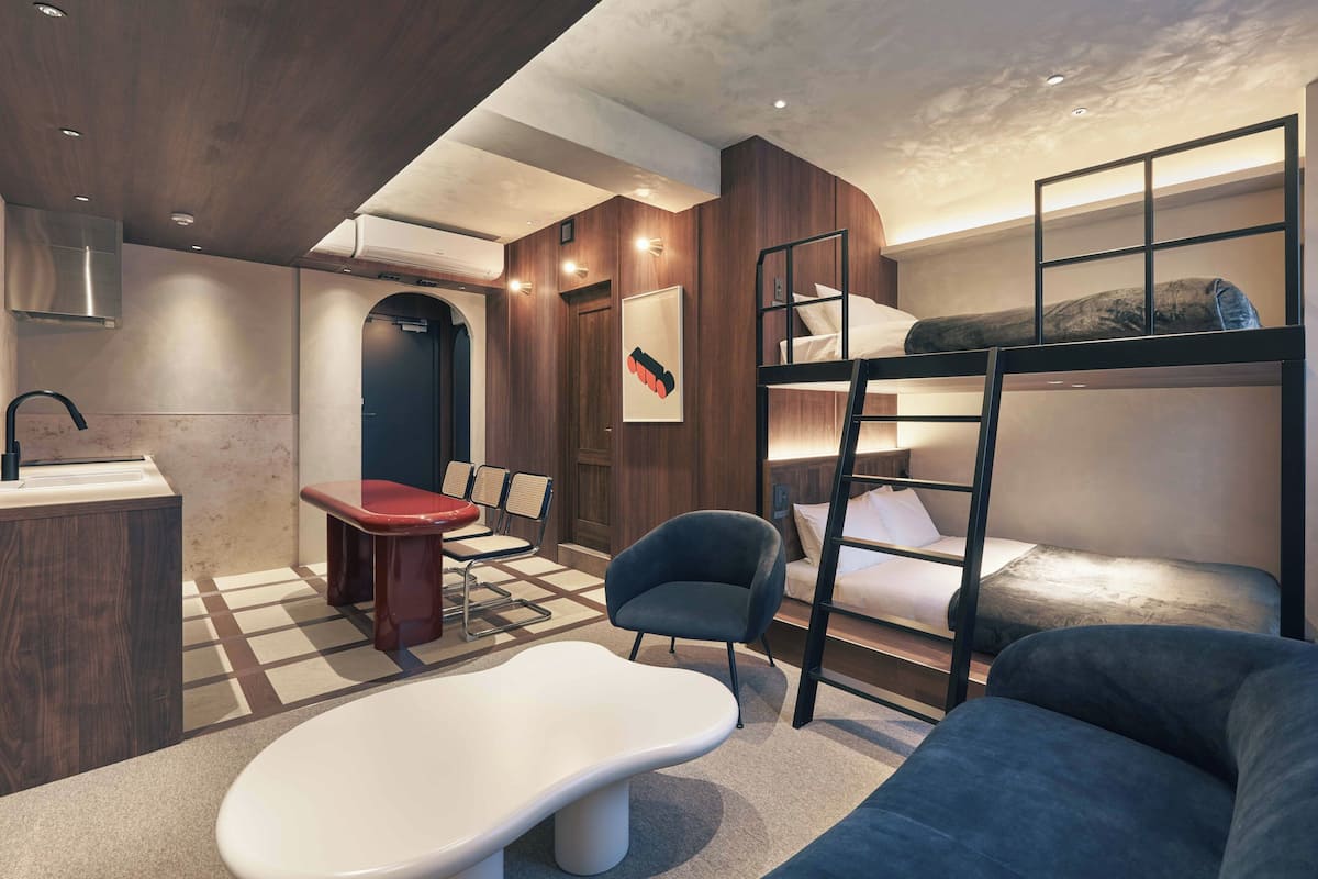A modern room with a bunk bed, a desk, a chair, and a sofa.