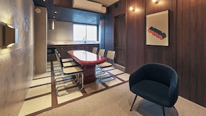 A modern kitchen with a central island, a dining area with a red table and chairs, and a dark blue armchair. - illi Noa Hamamatsucho (Tokyo)