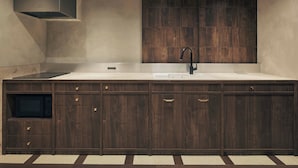 A modern kitchen with a built-in stove, a sink, and wooden cabinetry. - illi Noa Hamamatsucho (Tokyo)