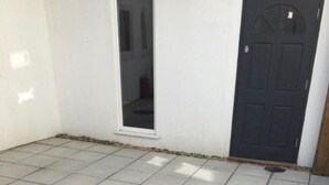 Un patio con baldosas, una puerta y una ventana.