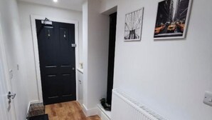 Un pasillo con piso de madera, una puerta negra y un radiador blanco.