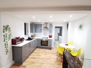 Una cocina moderna con armarios grises, una isla central y un área de comedor con sillas amarillas.
