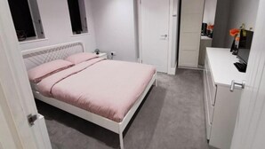 Un dormitorio con cama, mesita de noche, armario y espejo.