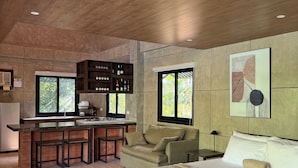 A modern bedroom with a large bed, a sofa, a small kitchen area, and a dining table. - Islas Moriones Beach Resort (Santa Cruz)