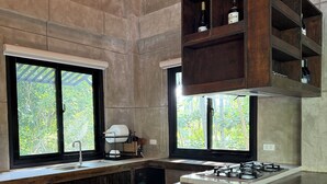 A modern kitchen with a long counter, built-in shelves, and large windows overlooking greenery. - Islas Moriones Beach Resort (Santa Cruz)